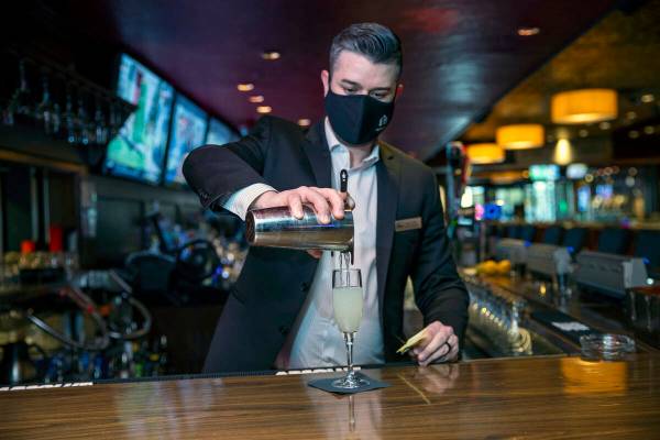 El director de bebidas, Sam Pulliam, sirve un cóctel de época ғage and the PineӠ mientras e ...