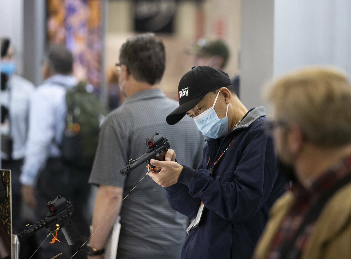 Tao Huang, en el centro, con iRay Technology, mira los visores láser durante la feria de tiro, ...