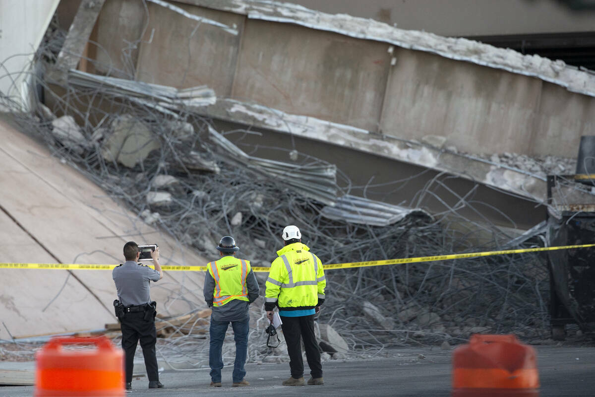 Un agente de policía de Las Vegas y empleados de Las Vegas Paving Corp. inspeccionan los daño ...