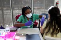 Adwoa Fosu pone una inyección a Olivia Ramírez, de Las Vegas, en un puesto de vacunación con ...