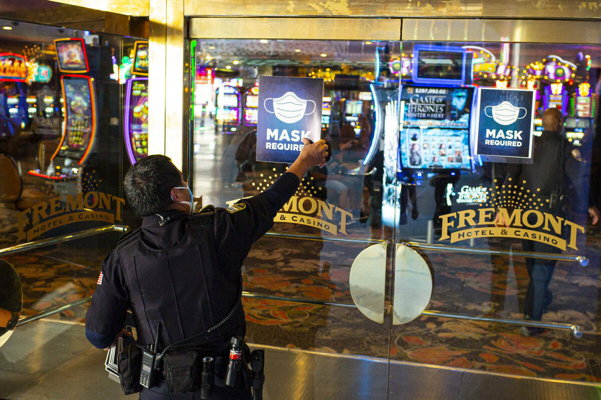 Un agente de seguridad retira los letreros que exigen el uso de cubrebocas en el hotel-casino F ...