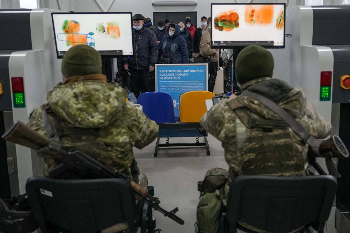 Militares ucranianos escanean las pertenencias de las personas que cruzan de las zonas controla ...