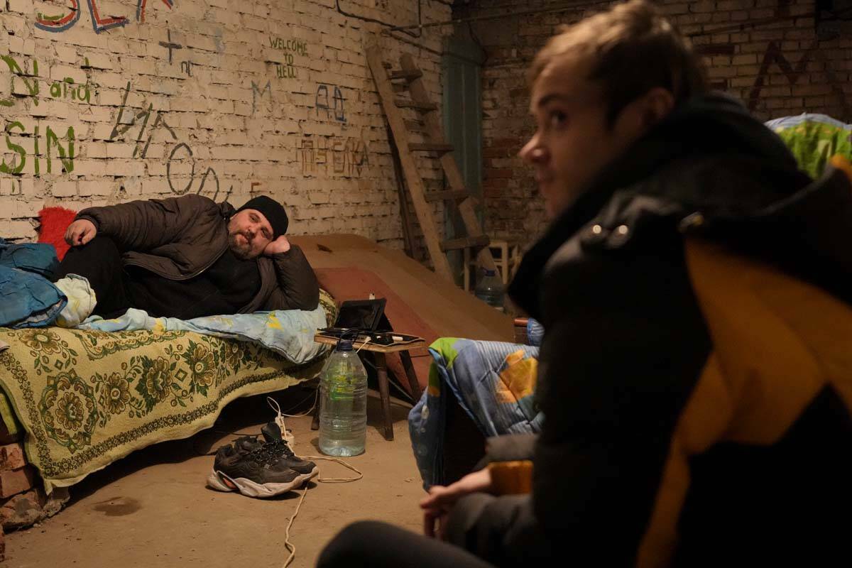 Personas acostadas en camas improvisadas en un refugio en el sótano de un edificio de apartame ...