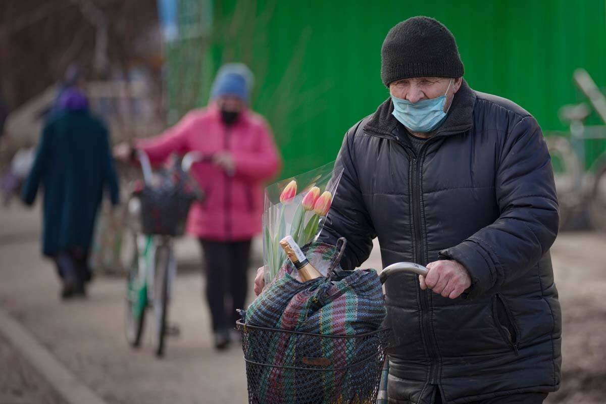 Un hombre lleva bolsas y un ramo de tulipanes en una bicicleta en Stanytsia Luhanska, el único ...