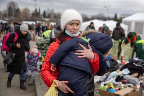 Una mujer carga a su hijo mientras llega al paso fronterizo de Medyka tras huir de Ucrania, en ...