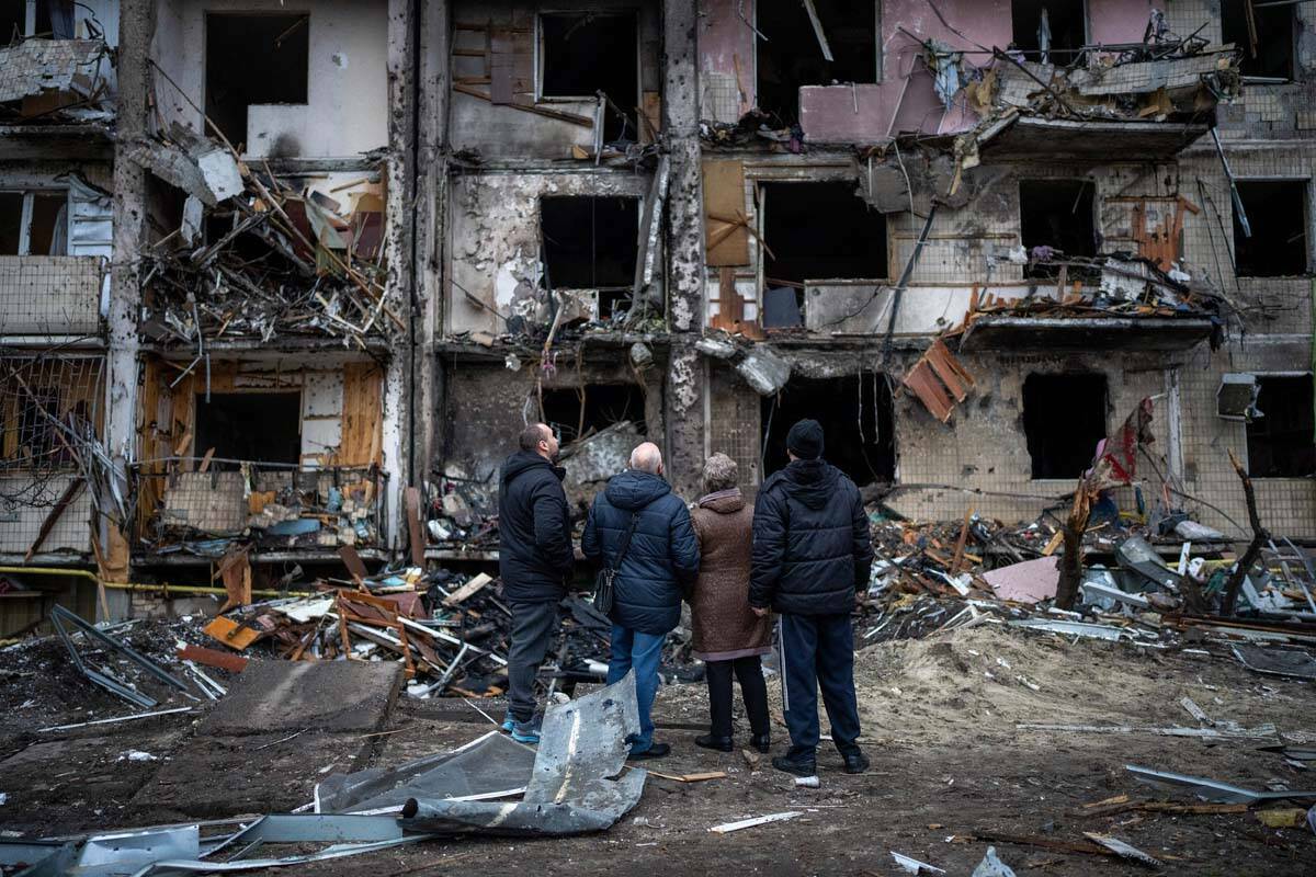 Personas observan los daños causados por un ataque con cohetes en la ciudad de Kiev, Ucrania, ...