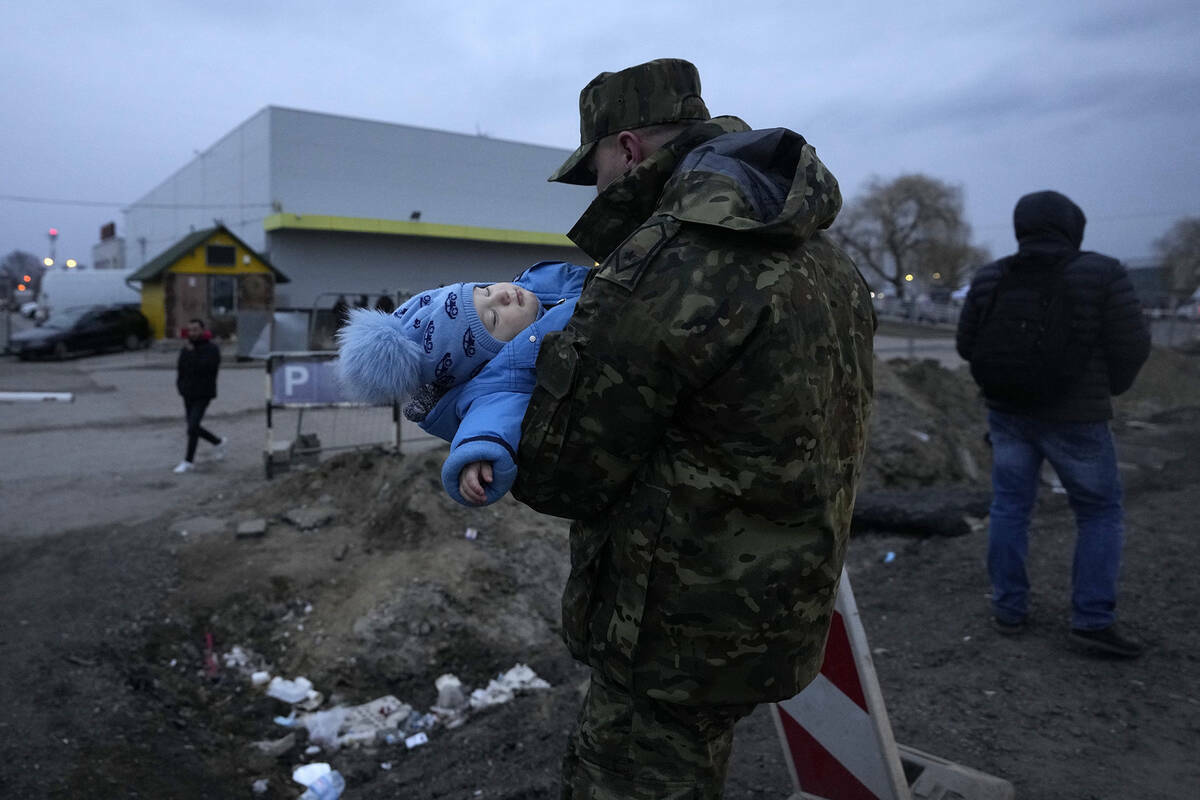 Un soldado polaco lleva a un bebé de una refugiada ucraniana a su llegada al paso fronterizo d ...