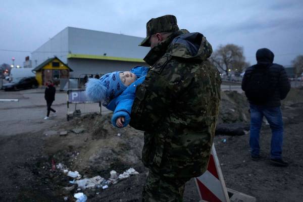 Un soldado polaco lleva a un bebé de una refugiada ucraniana a su llegada al paso fronterizo d ...