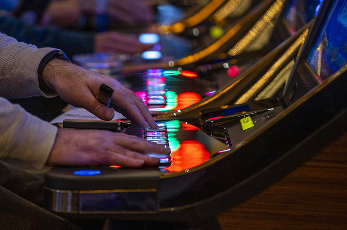 Un cliente juega a una máquina tragamonedas con otras personas cercanas en Red Rock Casino el ...