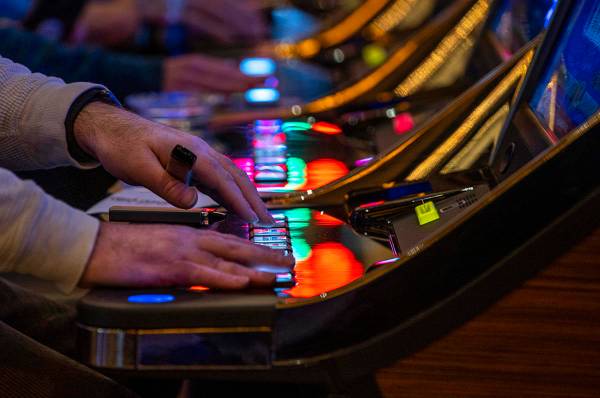 Un cliente juega a una máquina tragamonedas con otras personas cercanas en Red Rock Casino el ...