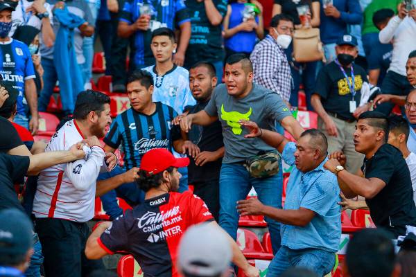 Aficionados de Querétaro y Atlas se enfrentan durante un partido de la liga mexicana de fútbo ...