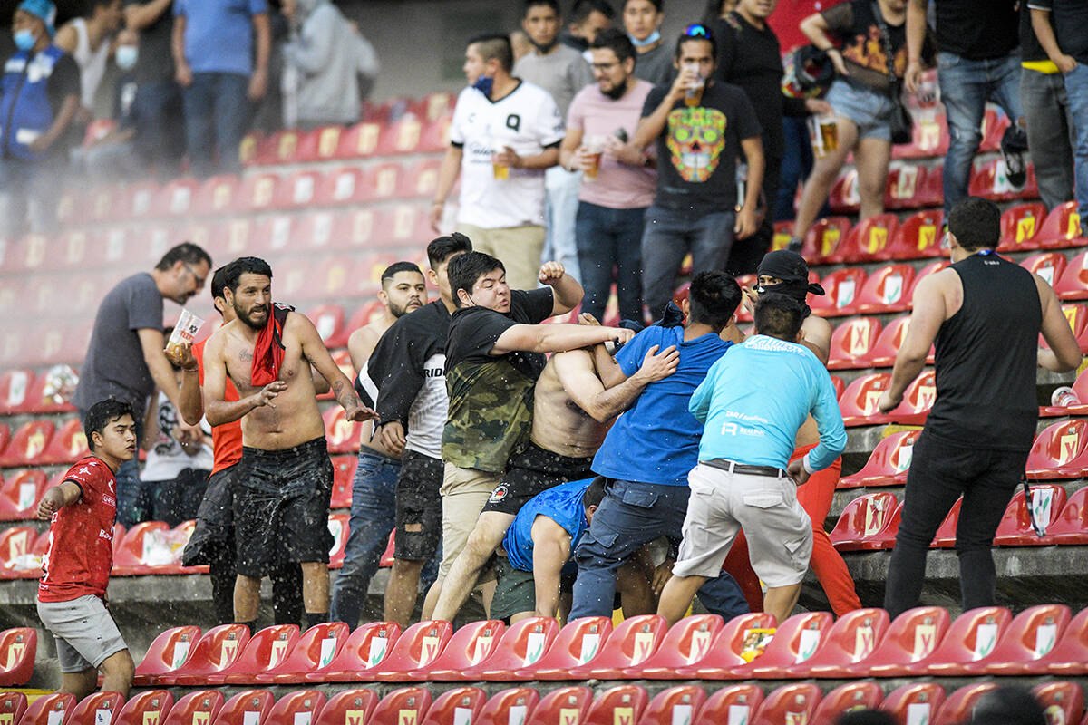 Aficionados riñen durante un partido de la liga mexicana de fútbol entre el anfitrión Queré ...