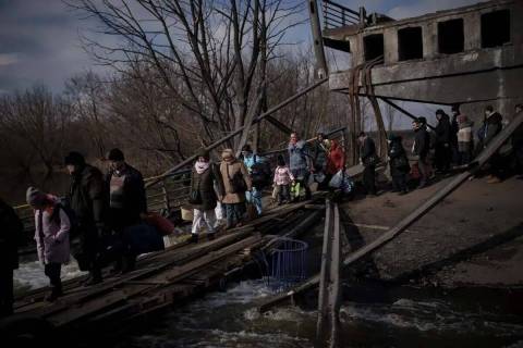 Ucranianos cruzan un camino improvisado bajo un puente destruido mientras huyen de Irpin, en la ...