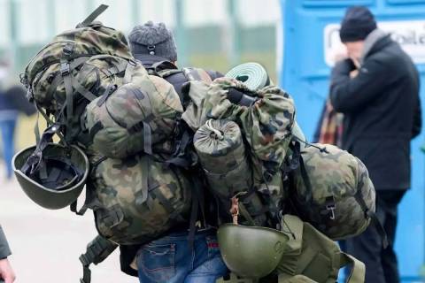 ARCHIVO - Un hombre lleva equipo de combate mientras sale de Polonia para luchar en Ucrania, en ...