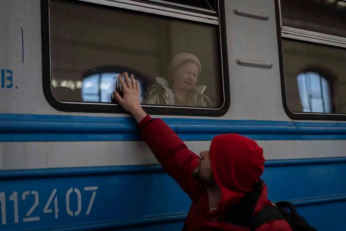 Desplazados ucranianos en un tren con destino a Polonia se despiden en Lviv, oeste de Ucrania, ...