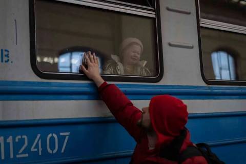 Desplazados ucranianos en un tren con destino a Polonia se despiden en Lviv, oeste de Ucrania, ...