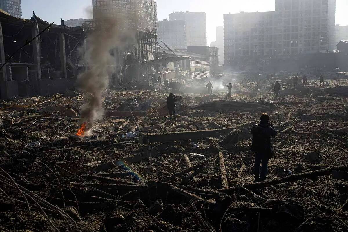 Gente se reúne en medio de la destrucción causada tras el bombardeo de un centro comercial, e ...