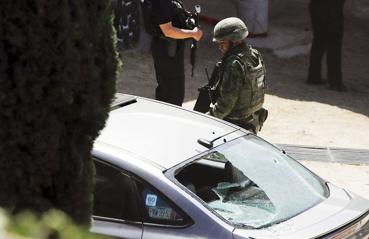 Un soldado se para junto a un automóvil con la ventana rota por las balas en el sitio de pelea ...