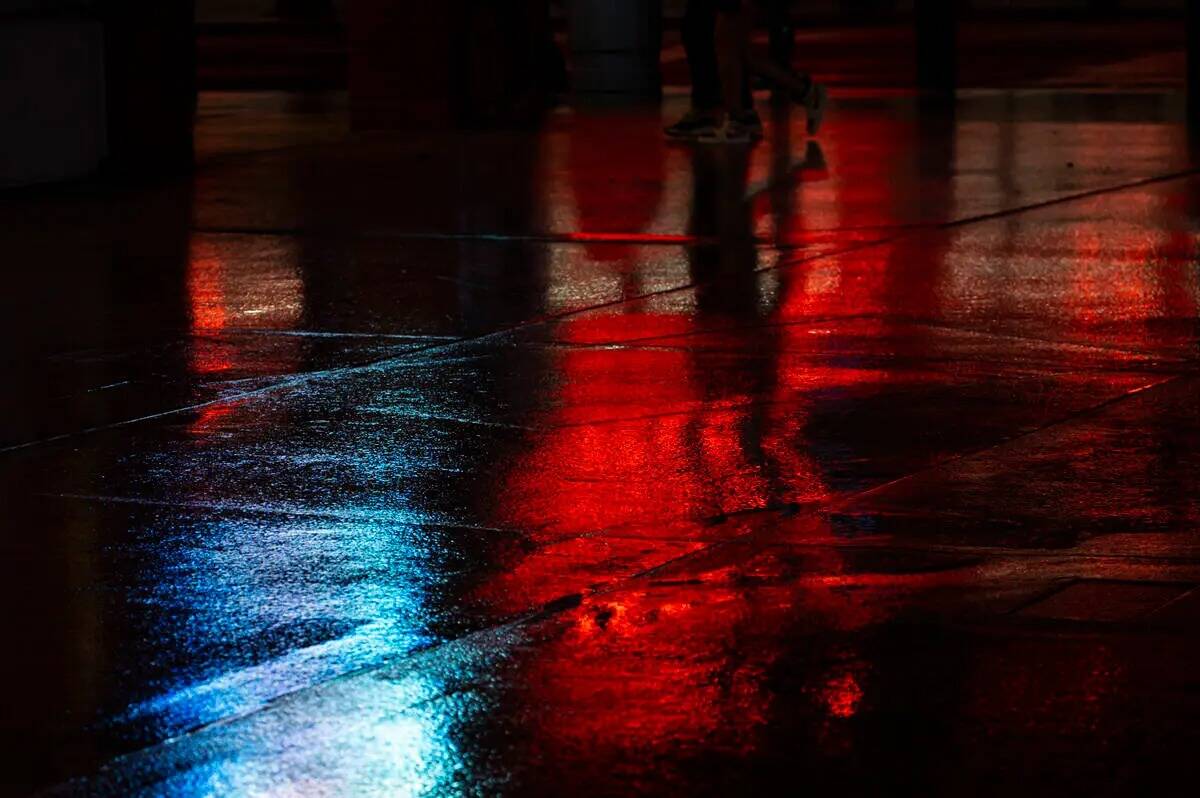 Pantallas y luces de neón se reflejan en el agua mientras la lluvia cae a lo largo de Fremont ...