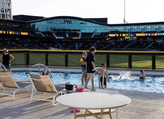 Unos niños nadan mientras esperan a que comience el partido inaugural de Las Vegas Aviators co ...
