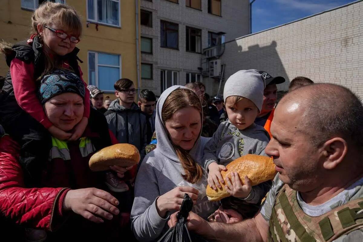 Un voluntario, a la derecha, distribuye ayuda humanitaria en el patio de una escuela en Chernih ...