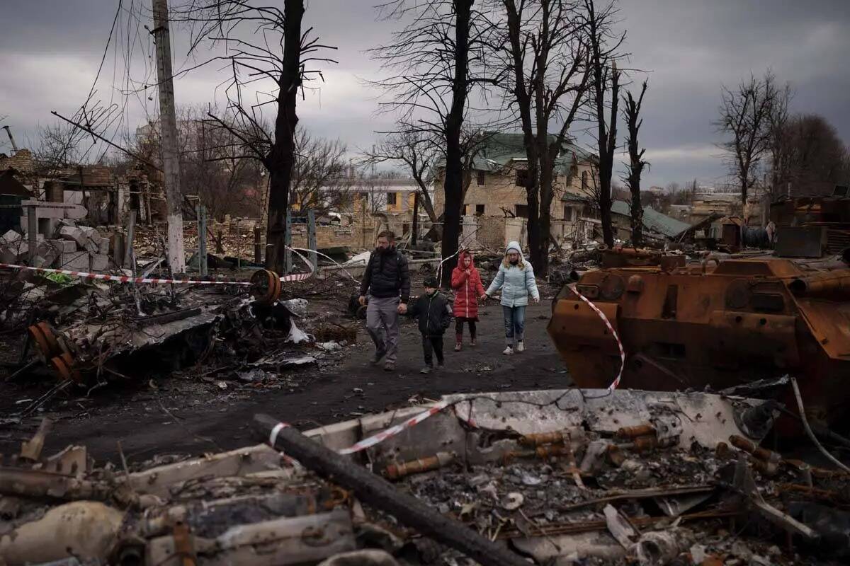 Una familia camina entre tanques rusos destruidos en Bucha, en las afueras de Kiev, Ucrania, el ...