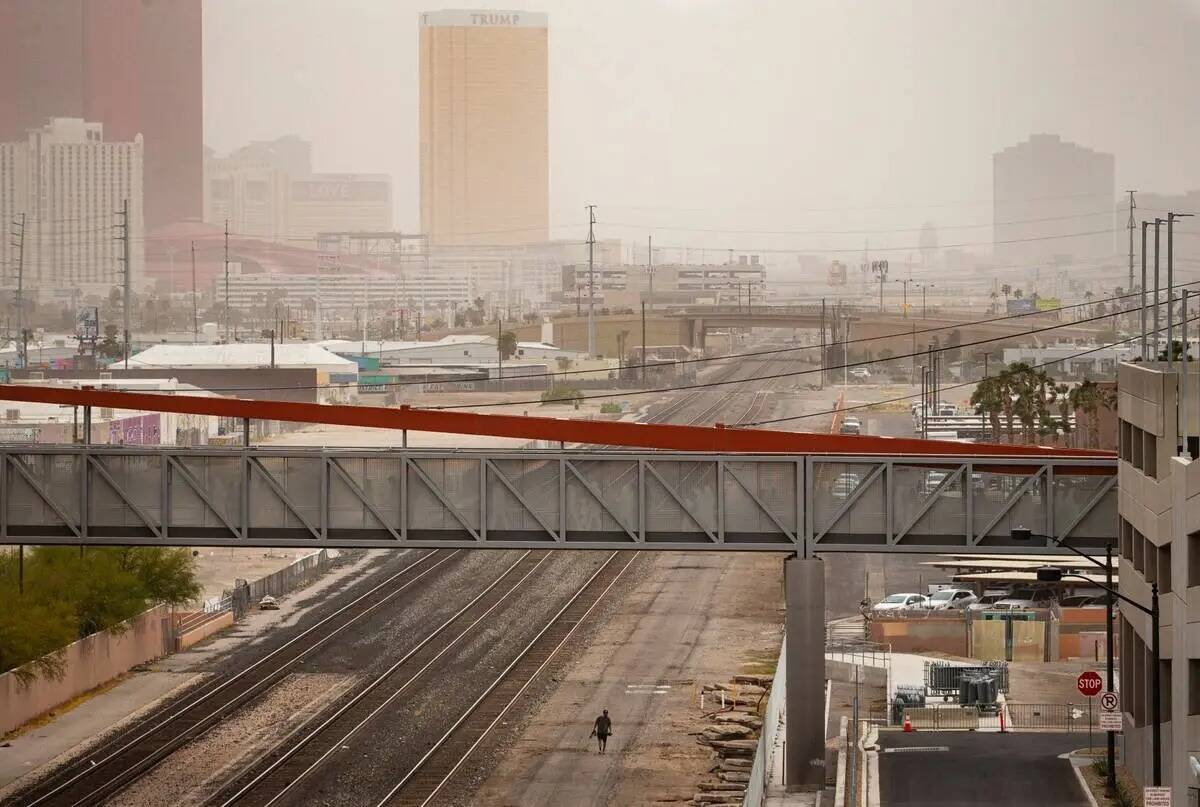 Un hombre camina junto a las vías del tren mientras los vientos traen una tormenta de polvo so ...