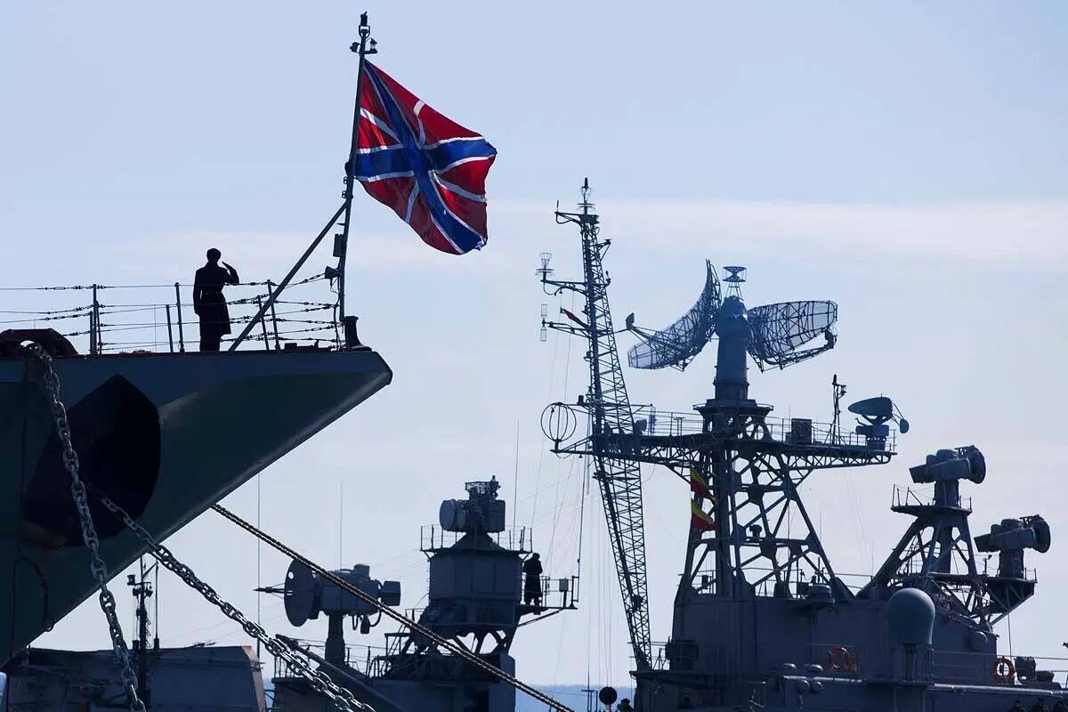 Un marinero ruso saluda en la proa del crucero de misiles Moskva, a la izquierda, mientras la t ...