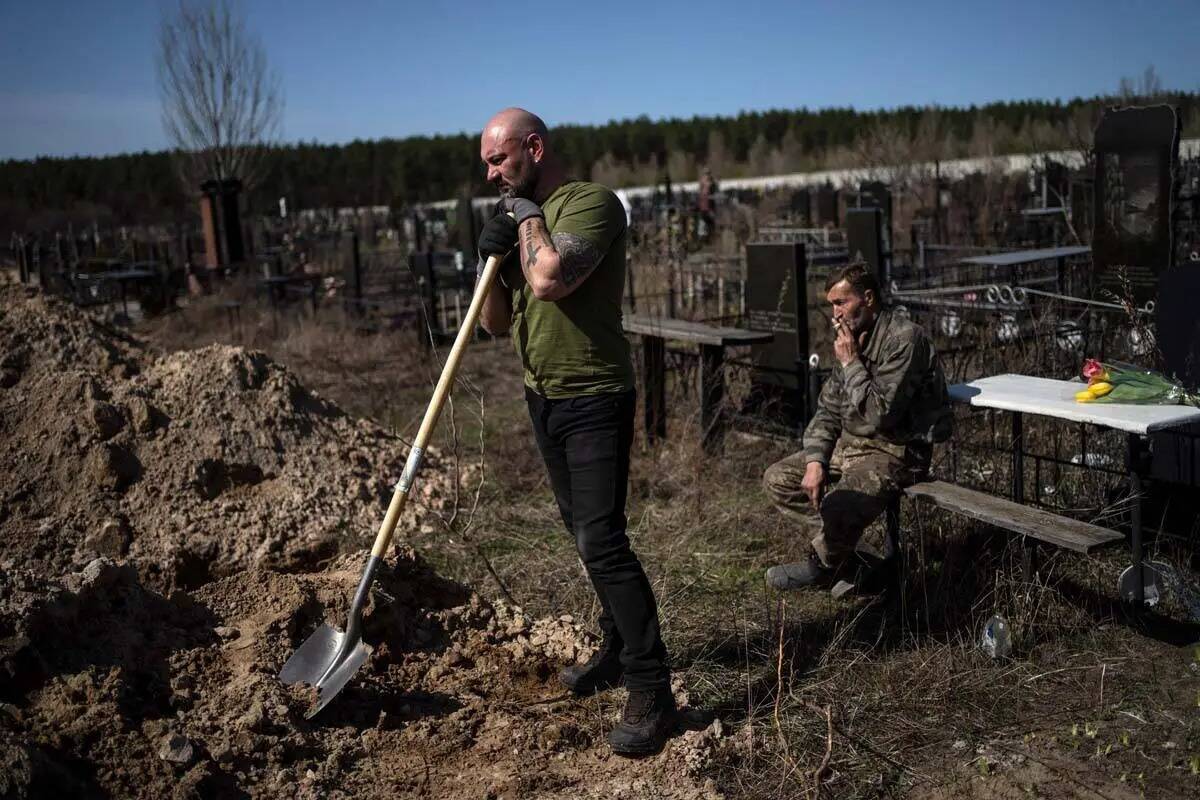 El trabajador del cementerio Vladislav, a la izquierda, hace una pausa en su trabajo durante el ...