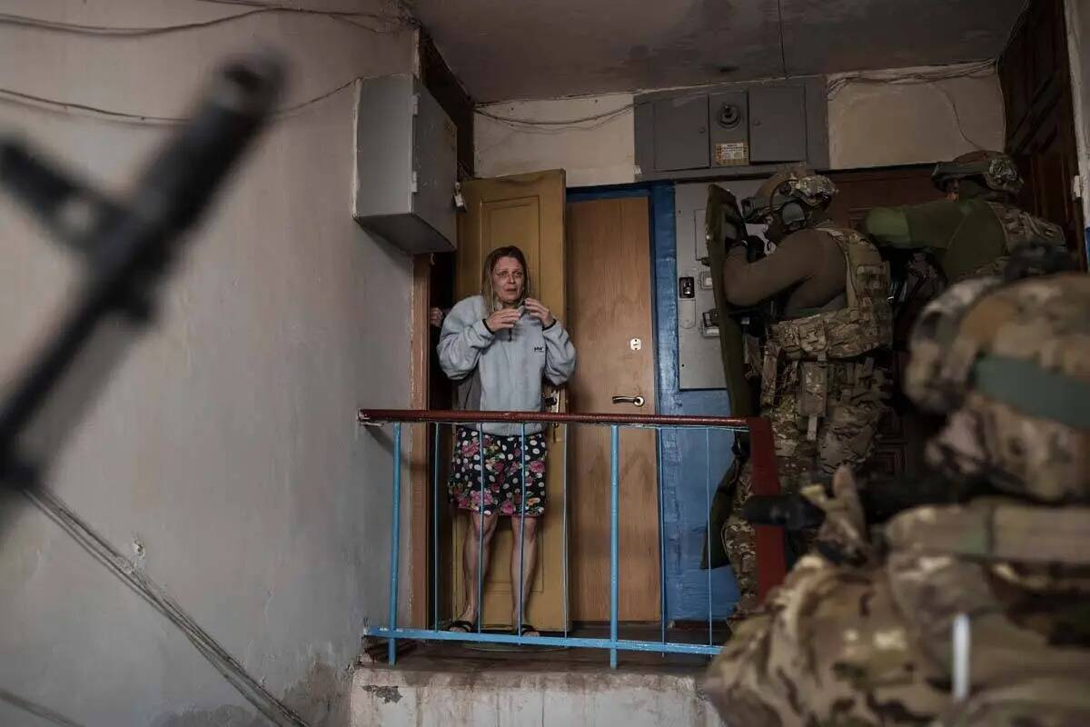 Una mujer mira mientras los militares del Servicio de Seguridad de Ucrania (SBU) entran en un e ...