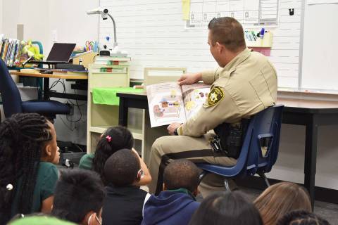 El capitán de LVMPD, Timothy Hatchett, lee un libro ante un grupo de estudiantes como parte de ...