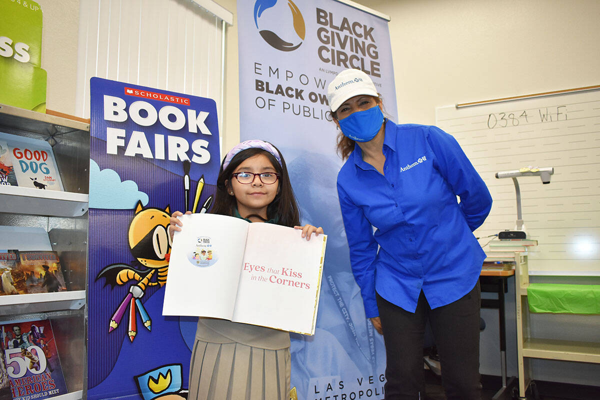 Una estudiante posa con un libro al lado de la representante de Anthem Blue Cross Blue Shield, ...