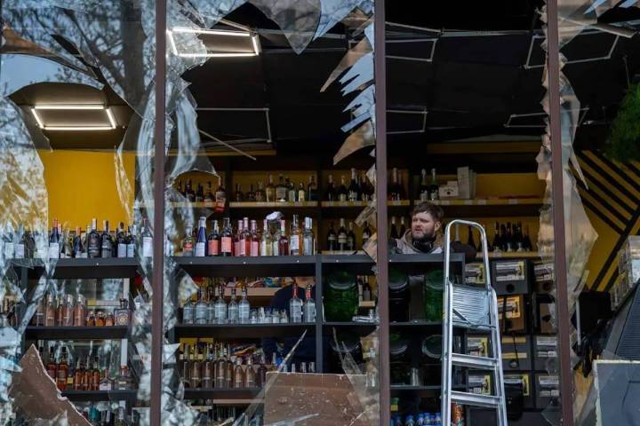 El propietario de una licorería observa los daños causados en su tienda por una explosión en ...