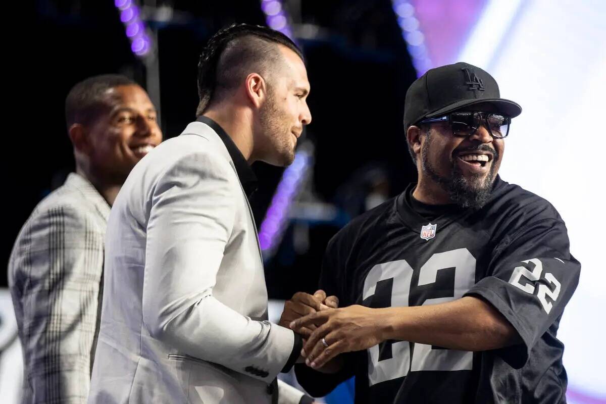 Ice Cube, a la derecha, estrecha la mano del qb de los Raiders, Derek Carr, en el escenario dur ...