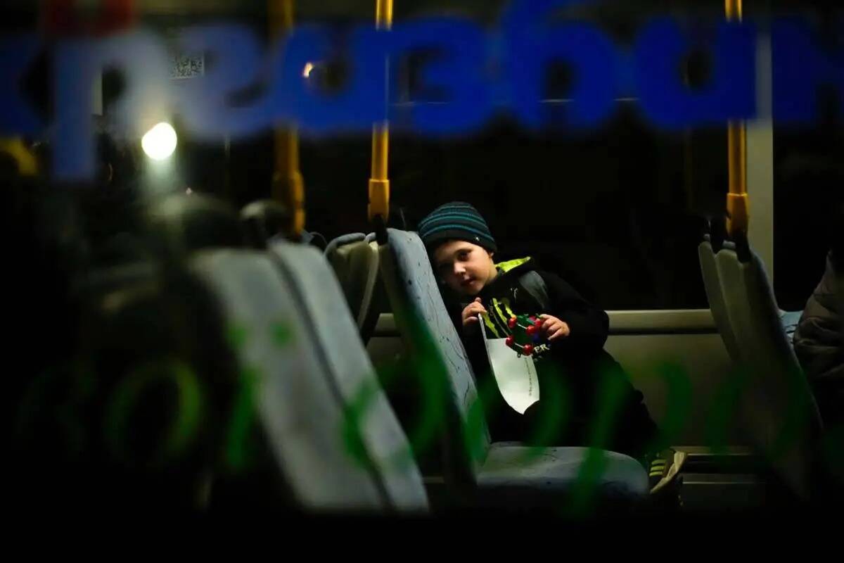 Un niño que huyó de Mariupol con su familia espera en un autobús a su llegada a un centro de ...