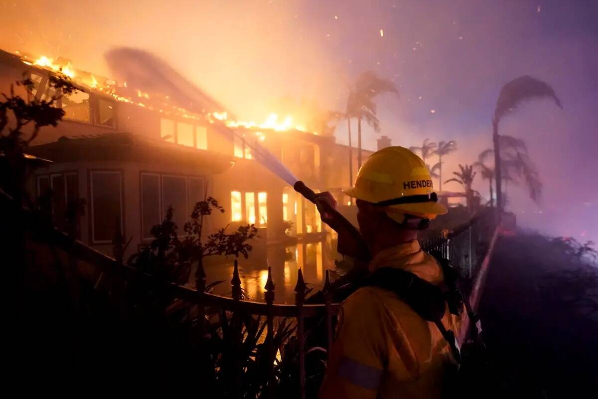 Un bombero trabaja para apagar una estructura que arde durante un incendio forestal el miércol ...