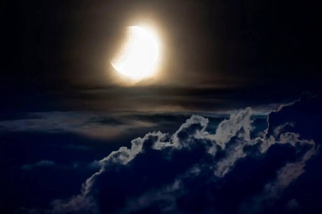 Comienza un eclipse lunar mientras la luna llena se pone sobre las colinas de las montañas del ...