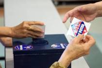 Archivo.- Un trabajador electoral entrega a un votante una calcomanía que muestra que votó mi ...