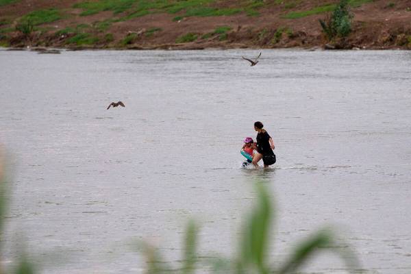 Una mujer y un niño cruzan el Río Bravo hacia Estados Unidos en Eagle Pass, Texas, el domingo ...