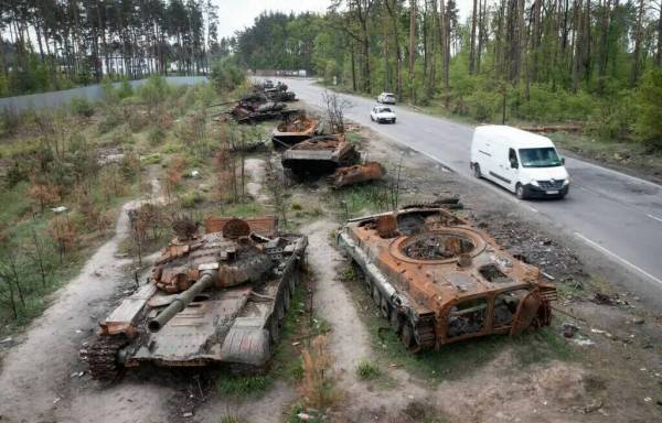 ARCHIVO - Autos pasan junto a tanques rusos destruidos en una reciente batalla contra los ucran ...
