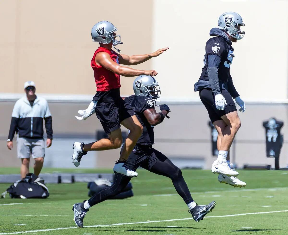 (De izquierda a derecha) El quarterback de los Raiders, Derek Carr (4), agarra aire junto al de ...
