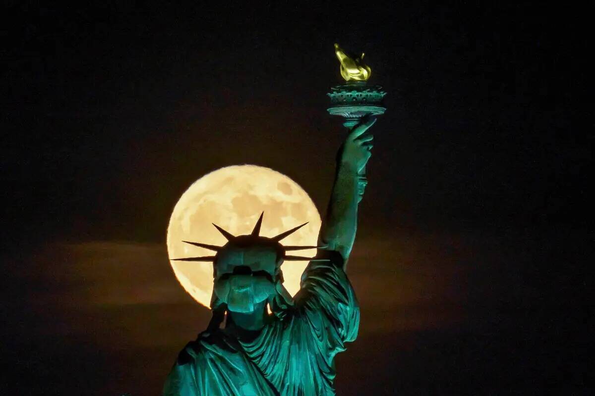 La Superluna de fresa se eleva frente a la Estatua de la Libertad en Nueva York, a última hora ...