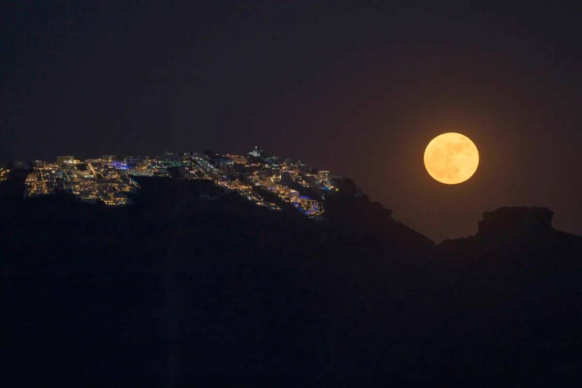 La superluna de fresa se eleva detrás del pueblo de Imerovigli en la caldera de Sandorini, en ...