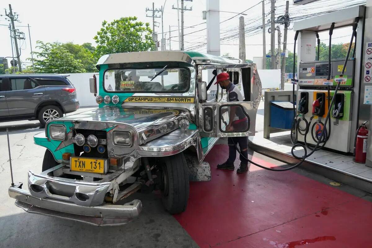 Un conductor de un jeepney de pasajeros estaciona su vehículo en una estación de gasolina en ...