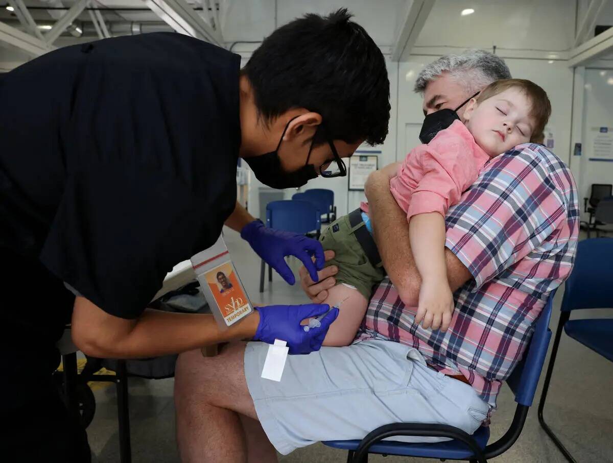 David Hopp sostiene a su hijo Aiden, de dos años, mientras recibe la vacuna COVID-19 de Grisly ...