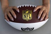 Nicole Adams sostiene un balón de fútbol americano con temática de los Raiders en su casa el ...