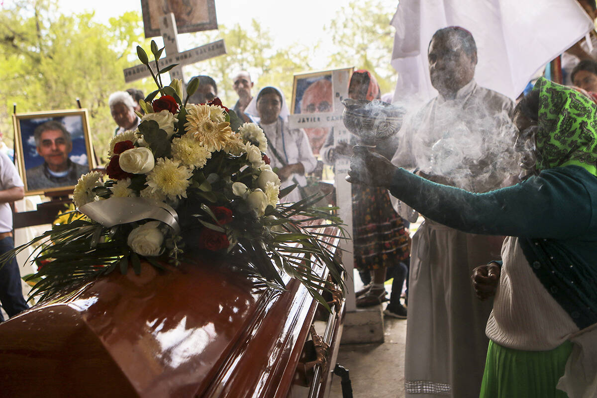 Una mujer quema incienso sobre los restos de los sacerdotes jesuitas Javier Campos Morales y Jo ...