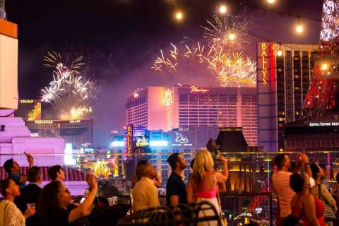 Los fuegos artificiales se disparan a lo largo del Strip de Las Vegas mientras la gente observa ...