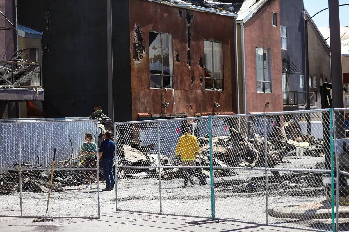 Los investigadores trabajan en la escena del enorme incendio que calcinó 10 edificios y docena ...