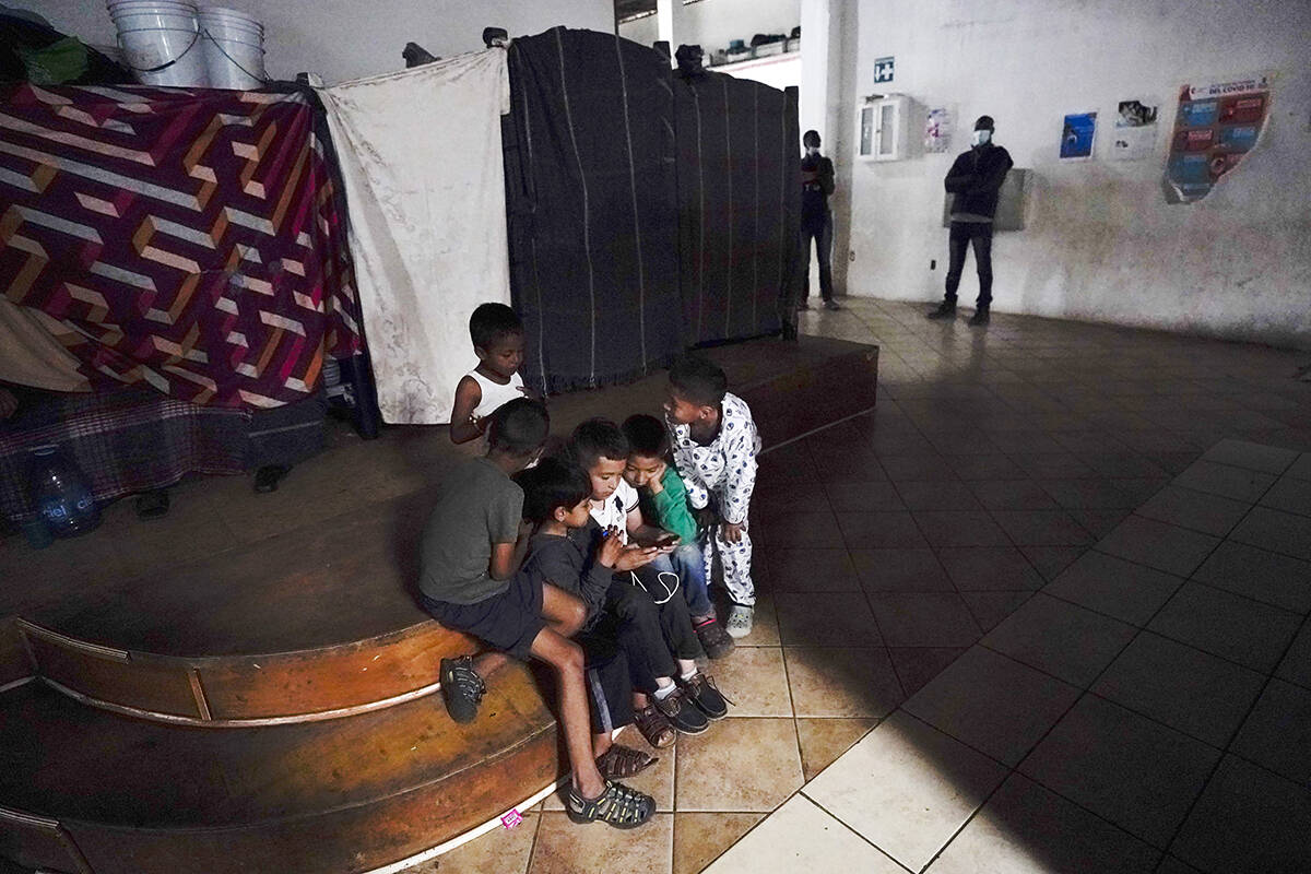 ARCHIVO.- Niños juegan un juego en un teléfono celular en un albergue para migrantes, 23 de m ...